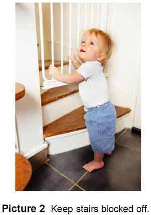 Small child standing at the bottom of stairs that are blocked with a gate
