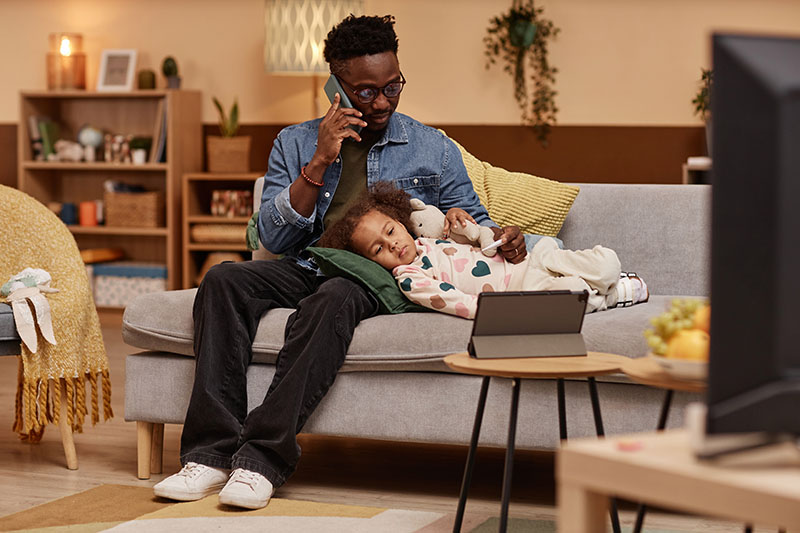 Father Sitting on Couch calling to schedule by telephone